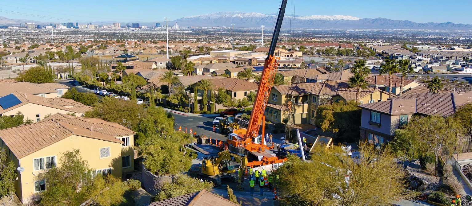 Pipe being lifted by crane as workers look on 