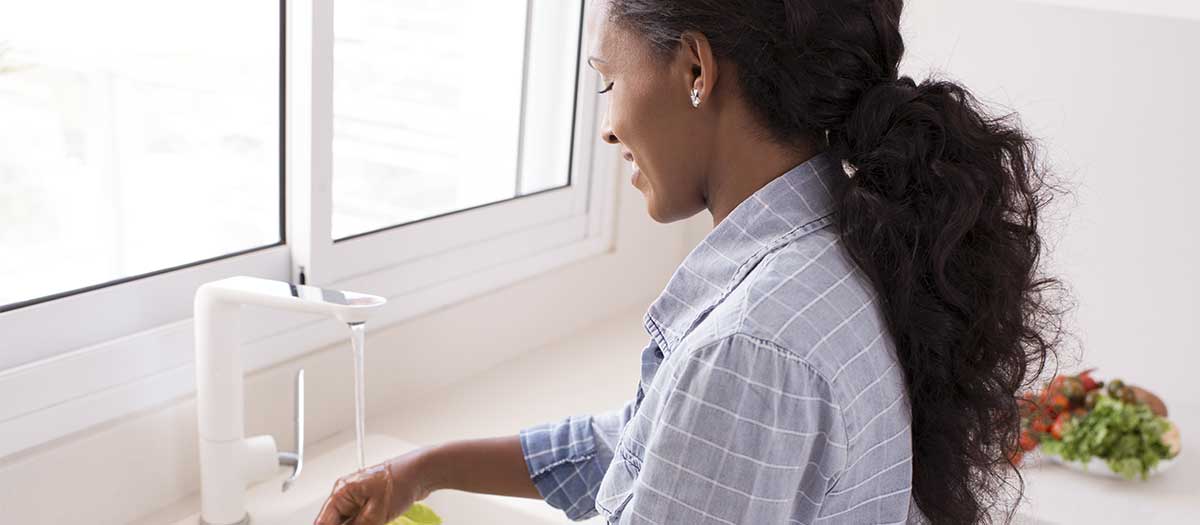 woman washing vegetables at kitchen sink