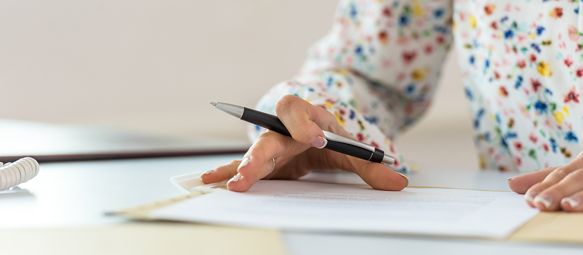 Woman with pen signing legal paper